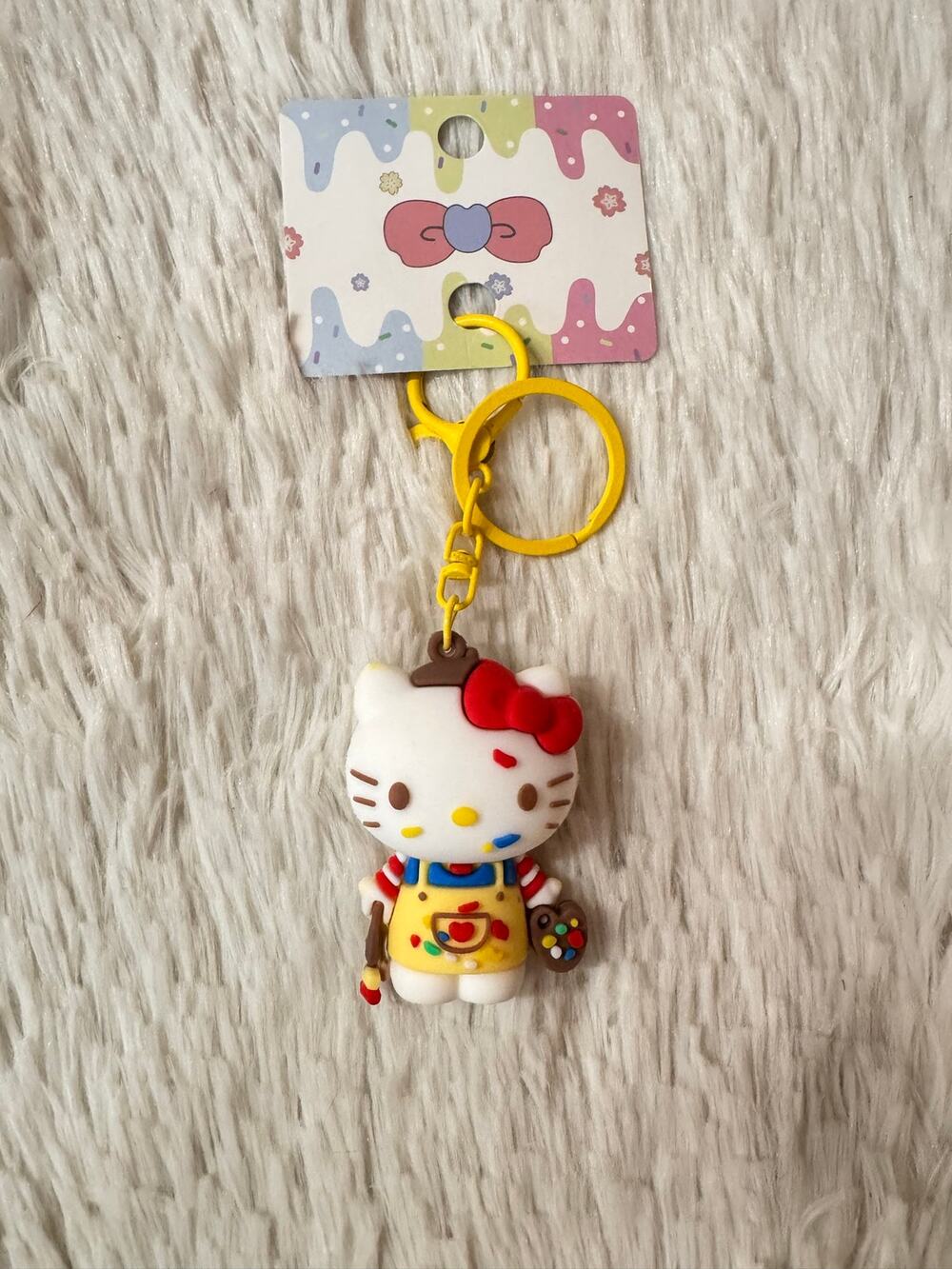 Hello Kitty keychain bow yellow overalls with paint splatters, and paintbrushes